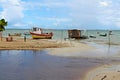 Boats and a fisherman wooden hut in middle of beach water.