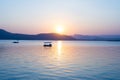 Boats floating on Lake Pichola with colorful sunset reflated on water beyong the hills. Udaipur, Rajasthan, India. Royalty Free Stock Photo