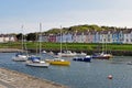 Boats moored in the harbour with the different coloured brightly coloured houses in the background in Wales