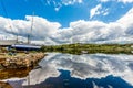 Boats out of the water with clouds reflecting in the water at Clifden harbor at high tide and the village in the background Royalty Free Stock Photo