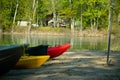 Boats pulled onto shore green canoe yellow and red kayaks Royalty Free Stock Photo