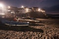 Boats pulled up on sand for night with surrounding street lights illuminating the buildings and beach Royalty Free Stock Photo