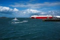 Boats and red cargo ship on sea under cloudy blue sky Royalty Free Stock Photo