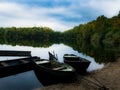 Boats on reflective sea water with trees in background and cloudy blue sky