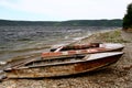 Boats on the river bank in summer in cloudy weather. Old metal boats lie on the rocky shore of a river bay with steep steep banks Royalty Free Stock Photo