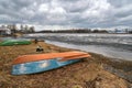 Boats on the shore of a frozen lake. Spring clouds over a melting pond Royalty Free Stock Photo