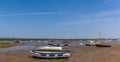 Boats on the shore and moored in Brancaster Bay near Burnham, Norfolk, UK