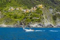 Boats speed past the Cinque Terre village of Corniglia, Italy Royalty Free Stock Photo