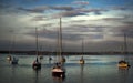 sail boats wait to go into harbor at sunset. Royalty Free Stock Photo