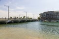 Boats and yachts docked in front of a luxury apartment with rippling green ocean water with cars driving across a bridge