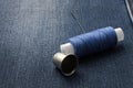 A bobbin of thread with a needle and a thimble. on denim background. close-up Royalty Free Stock Photo