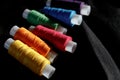 Bobbins of multicolored thread. A set of sewing thread reels on black and natural fabric. Several turns of thread of different bri Royalty Free Stock Photo