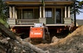 Bobcat excavator moves earth from under a jacked up house