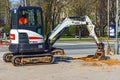 Bobcat mini excavator with bulldozer, rubber tracks in the city on the sidewalk