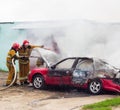 BOBRUISK, BELARUS - JULY 25, 2018: Two firemen extinguish a burning car, fire