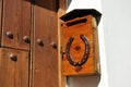 Buzon de cartas de madera con candado y herradura en la fachada de una vivienda unifamiliar