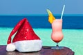 Bocal of drink is on a beach table with Santa hat