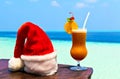 Bocal of drink is on a beach table with Santa hat