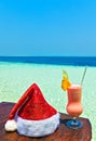 Bocal of drink is on a beach table with Santa hat