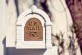 White wooden US mail letterbox with metal emboss eagle symbol on the front yard of a house. Editorial