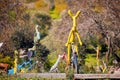 Yellow deer sculpture riding a rusty vintage bike in a children`s park. Abstract modern public art for children