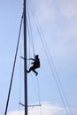 Young man hanging and repairs yacht mast