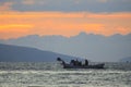 A fisherman who tries to catch fish in a tiny small boat in the Aegean Sea among the waves in a rainy day.