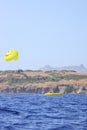 Parasailing on the sea, speed boat and couple on parachute with on mountain background.