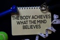 The Body Achieves What The Mind Believes write on a book isolated on black background. Workout concept