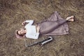 Body of a beautiful young woman in long dress lying on the dry grass next to the saxophone, blonde girl rests on the hay with a Royalty Free Stock Photo