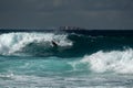 Body boarder surfing a large wave at South Maroubra at sunrisewith a ship far in the background