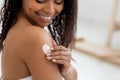 Body Care Concept. Smiling Beautiful Black Woman Applying Moisturizing Lotion On Shoulder Royalty Free Stock Photo