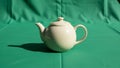 Body curved spout and loop handle sitting atop a green fabric Royalty Free Stock Photo