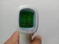 Body infared thermometer in hand, checking at 36 degree on white background closeup.