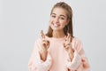 Body language. Superstitious teenager girl with blonde hair and pretty face crossing fingers for good luck, hoping her Royalty Free Stock Photo