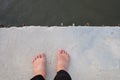 Female barefoot standing on hard cement pathway with dark river below Royalty Free Stock Photo