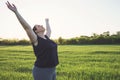 Overweight woman practicing yoga on meadow.