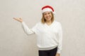 Body positive. A happy plus size girl with a short haircut stands against a light wall in a Santa Claus Christmas hat, with her Royalty Free Stock Photo