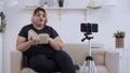 Body positivity - confident fat woman feminist lying on a couch and making a video on her phone for her followers about