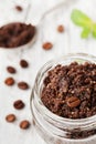 Body scrub of ground coffee, sugar and coconut oil in glass jar on white rustic table, homemade cosmetic for peeling and spa Royalty Free Stock Photo