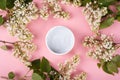 Body scrub on a pink background among the branches of a white lilac top view, beauty, skin care, skin cleansing, cosmetics