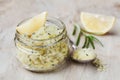 Body scrub of sea salt with lemon, rosemary and olive oil in glass jar on stone table