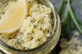 Body scrub of sea salt with lemon, rosemary and olive oil in glass jar on stone table