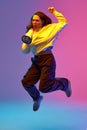 Body size portrait of young lady jumping loudly shouting to megaphone against gradient colorful background in neon light