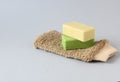 Close-up body washcloth made of natural fibers and two natural soaps on blue background with copy space