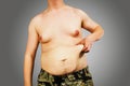 Body of young man with excess weight, keep belly fat, on a gray background