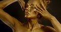 Bodyart of golden statue, woman is stroking her face and moving in black background Royalty Free Stock Photo