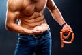 Bodybuilder athlete with naked torso playing muscles with smoked sausage in one hand and sausages on a neck Royalty Free Stock Photo