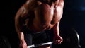 Bodybuilder does exercises with a barbell. Black smoke background. Slow motion