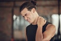 Bodybuilder experiencing a neck cramp in the gym. Fit young man with neck pain in the gym. Athletic muscular man with Royalty Free Stock Photo